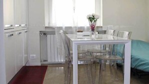 A compact living space with a dining area, a kitchenette, and a large window providing natural light.