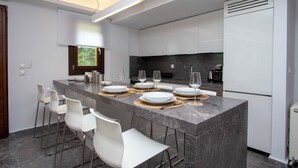 Een moderne keuken met een marmeren eiland, witte barkrukken en een ingebouwd fornuis.