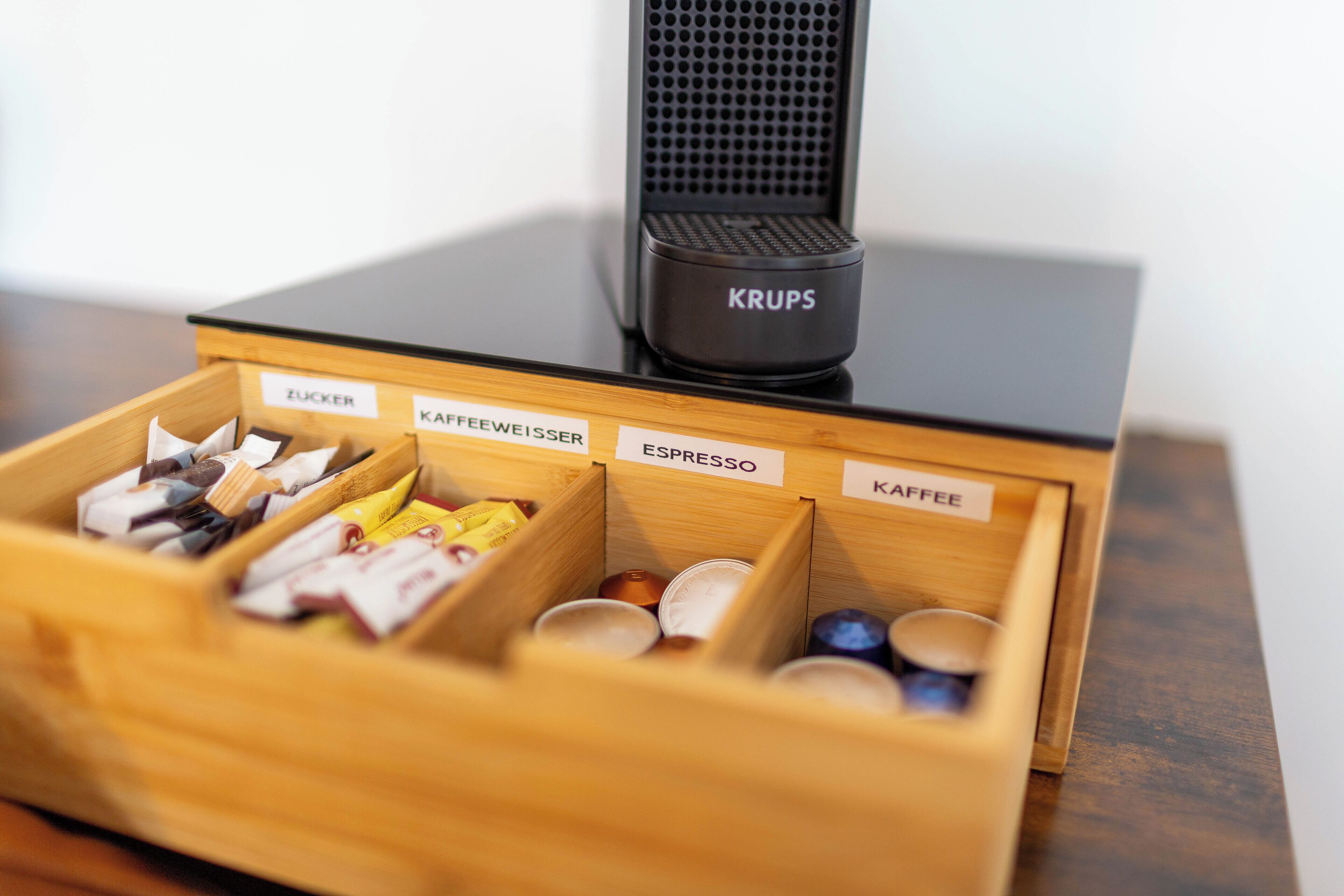 En kaffemaskine med afmærkede rum til 'Zucker', 'Kaffeeweiss', 'Espresso' og 'Kaffee'.