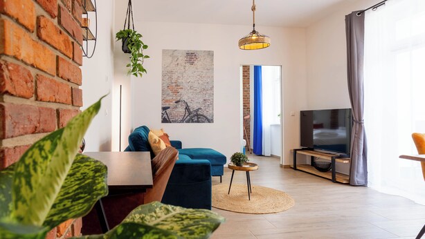 Una sala de estar moderna con un sofá azul, un televisor y una pared de ladrillo.