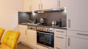 Una cocina moderna con gabinetes blancos, horno empotrado y cafetera.