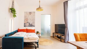 Una sala de estar moderna con cama, sofá, televisión y comedor.