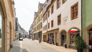 Una calle adoquinada bordeada de edificios históricos, algunos con tiendas y cafés.