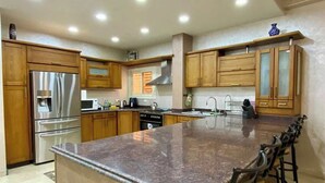 A modern kitchen with wooden cabinets, stainless steel appliances, and a granite countertop. - New Cairo Gem 3BR Villa w/ Garden, Near Shopping & Dining by Best of Bed'z (cairo)