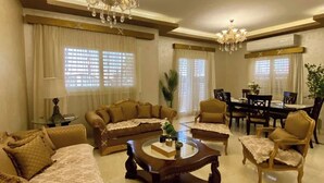A spacious living room with a large sofa set, a coffee table, and a dining area with chairs and a table. - New Cairo Gem 3BR Villa w/ Garden, Near Shopping & Dining by Best of Bed'z (cairo)