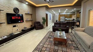 A modern living room with a flat-screen TV, leather sofas, a coffee table, and a patterned rug. - New Cairo Gem 3BR Villa w/ Garden, Near Shopping & Dining by Best of Bed'z (cairo)
