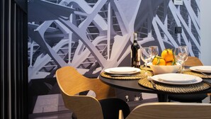 Un'elegante sala da pranzo moderna con un tavolo apparecchiato per due, con una bottiglia di vino, bicchieri e una ciotola di frutta.