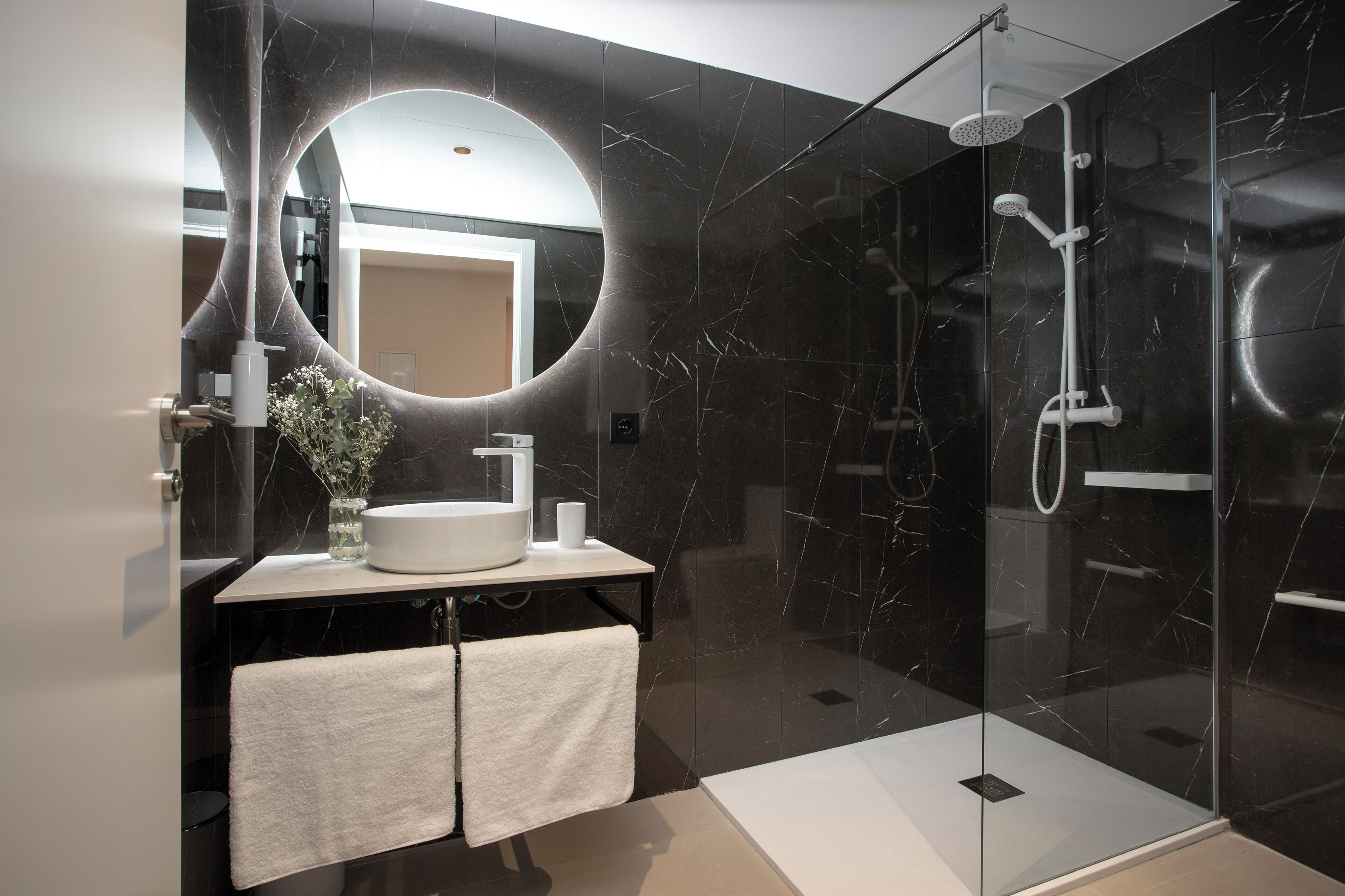 A modern bathroom with a large mirror, a sink, and a shower area.