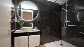 A modern bathroom with a large mirror, a sink, and a shower area.