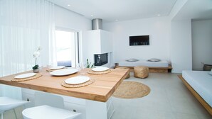 Une cuisine moderne avec un plan de travail en bois, des tabourets de bar blancs et un téléviseur encastré.