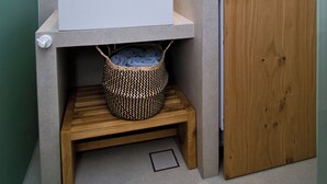 Une salle de bain moderne avec un grand miroir, un lavabo blanc, un banc en bois et un meuble en bois.