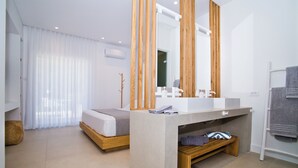 Une salle de bain moderne avec un grand miroir, un lavabo et un banc.