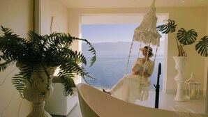 A room with a view of the sea, a hanging chair, and a potted plant. - Dali Nest Secret Garden Lake View Inn (Dali)