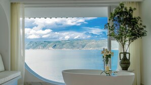 A bedroom with a large window, a white bathtub, a vase with flowers, and a green vase on a side table. - Dali Nest Secret Garden Lake View Inn (Dali)
