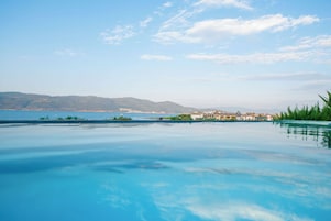Una piscina azul cristalina con vistas a montañas lejanas y una extensión de agua.