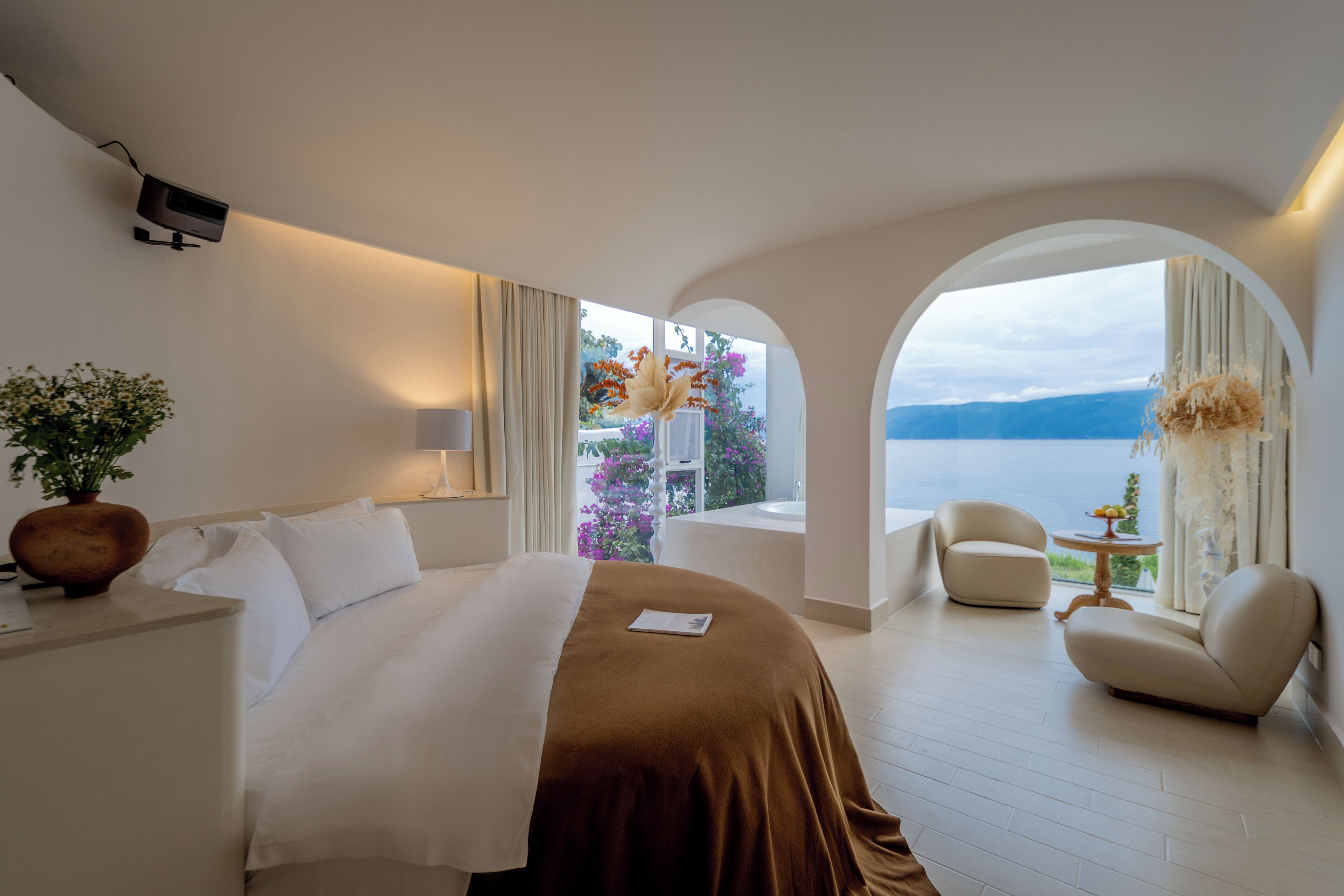 Una habitación de hotel con cama, escritorio, silla y vista al lago.