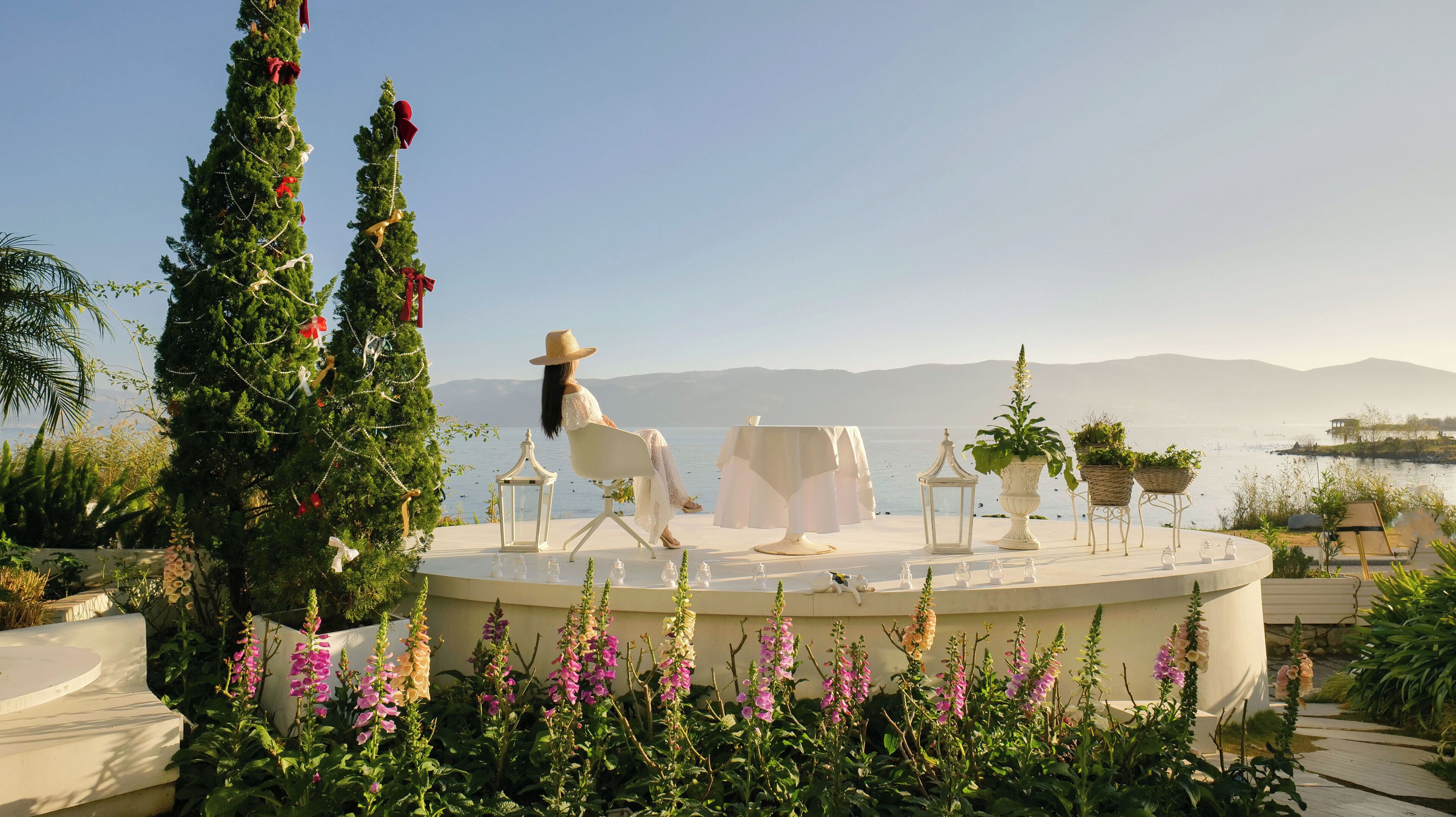 A circular outdoor seating area with a view of the sea, decorated with flowers and a Christmas tree.