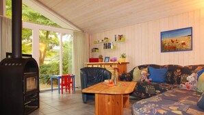 A cozy living room with a fireplace, a sofa, a coffee table, and a bookshelf. - Ferienhaus mit Sauna im Ferienpark Mirow (Mirow)