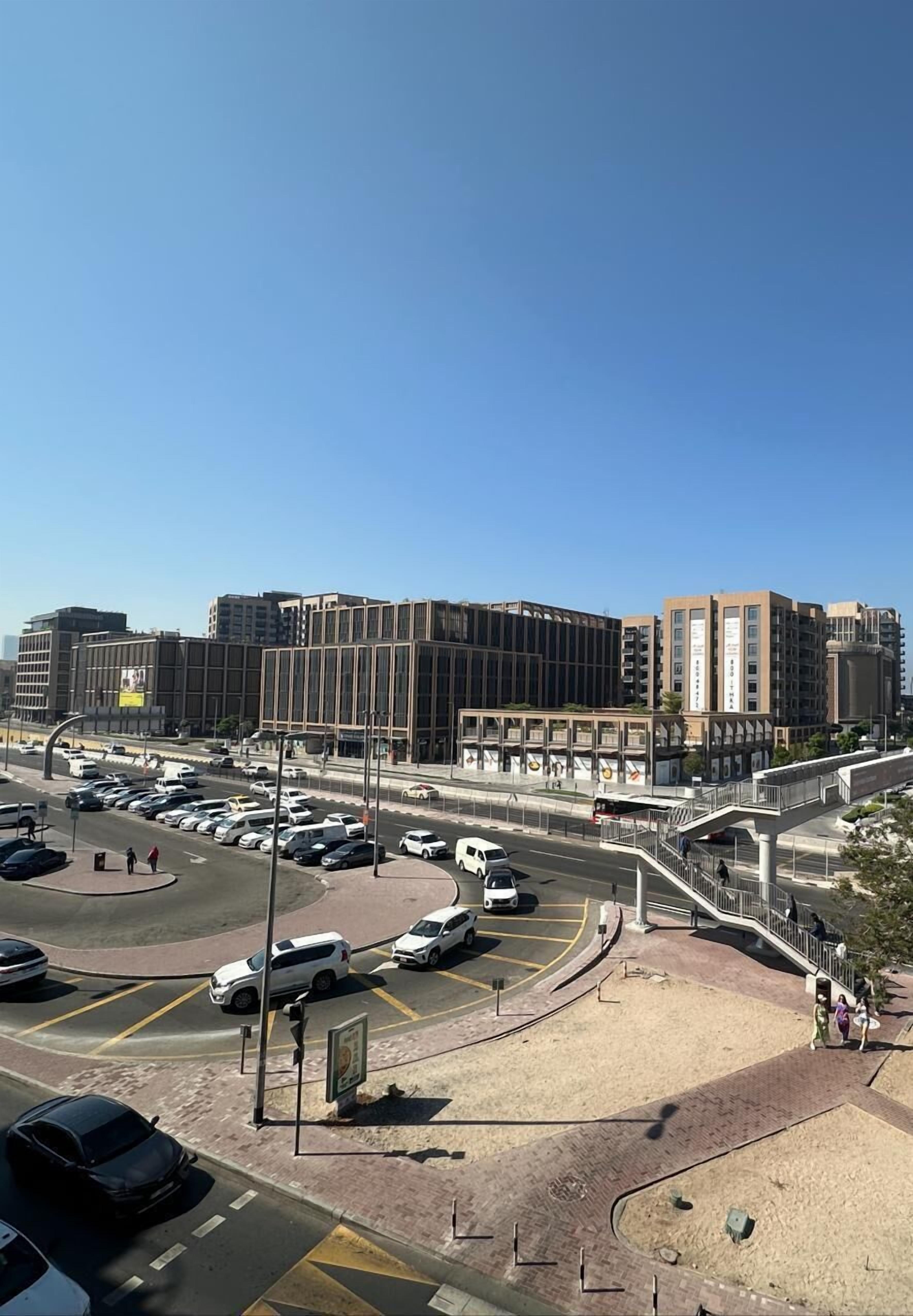 A modern urban intersection with a pedestrian bridge and a parking lot.
