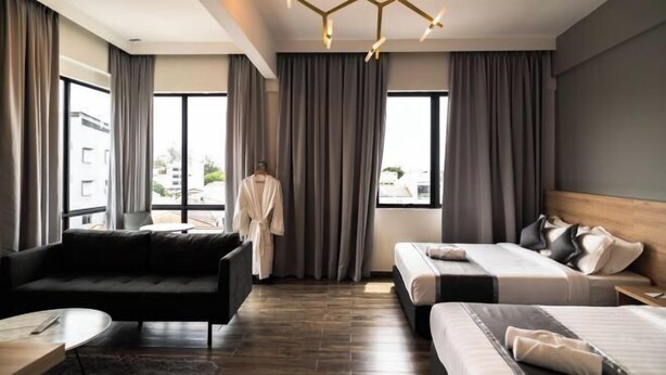 A modern hotel room with a sofa, two beds, a chandelier, and large windows. - DJ Citi Plaza Hotel & Suites (Kuala Terengganu)