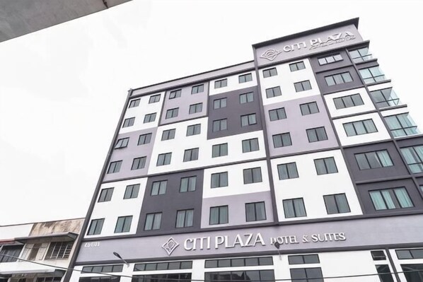 Un hotel de varios pisos con un letrero que dice 'CITI PLAZA HOTEL & SUITES'.