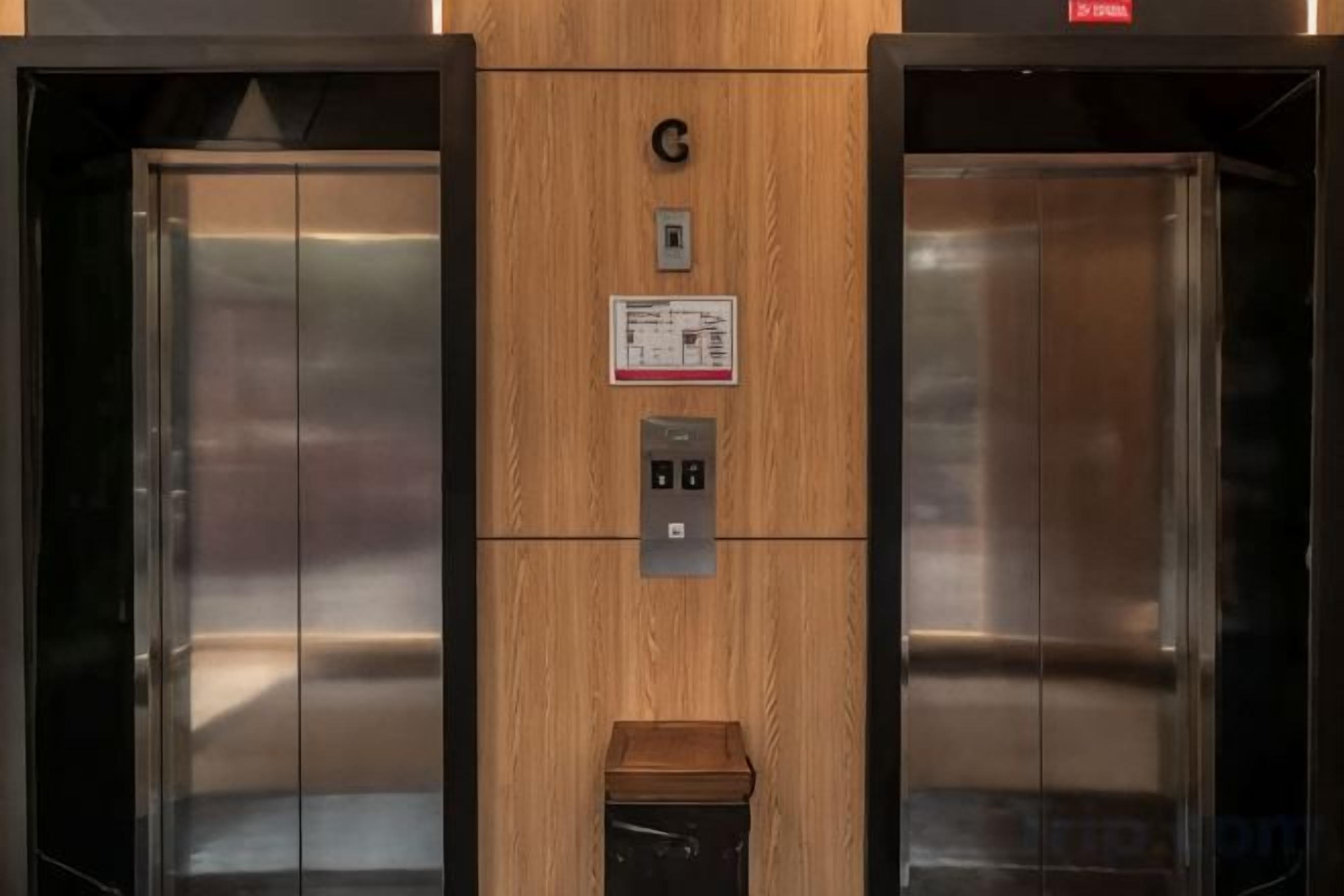 An elevator with a wooden panel, a control panel, and a sign.