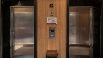 An elevator with a wooden panel, a control panel, and a sign.