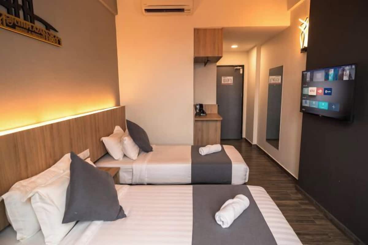 A hotel room with two beds, a TV, and a small kitchenette.