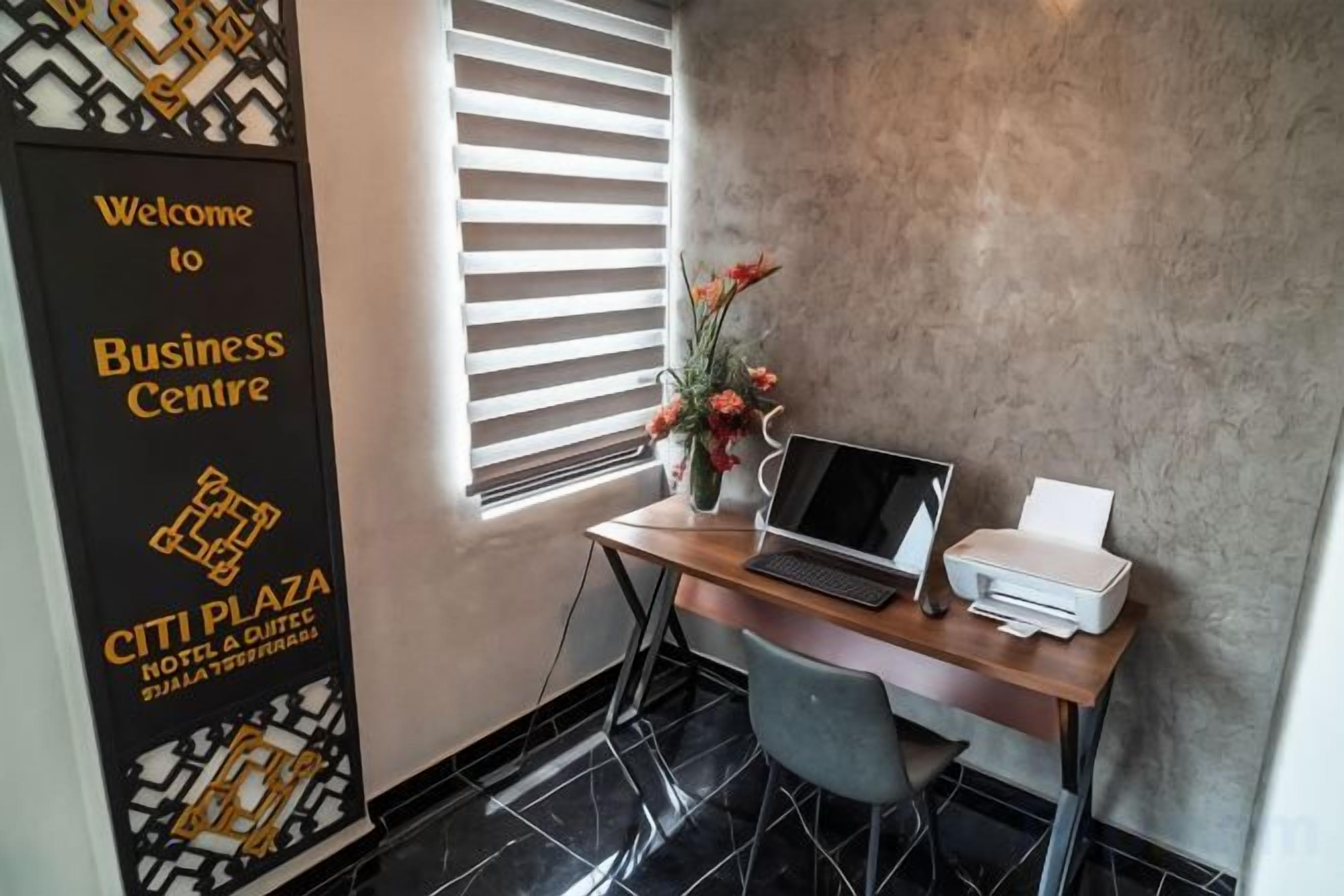 A business center with a desk, laptop, printer, and a welcome sign.