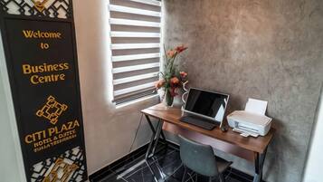 A business center with a desk, laptop, printer, and a welcome sign.