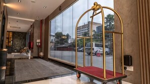 A hotel lobby with a large window, a reception desk, and a luggage cart. - DJ Citi Plaza Hotel & Suites (Kuala Terengganu)