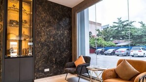 A lobby with a marble wall, a reception desk, a sofa, and a view of parked cars outside. - DJ Citi Plaza Hotel & Suites (Kuala Terengganu)