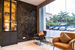 A lobby with a marble wall, a reception desk, a sofa, and a view of parked cars outside. - DJ Citi Plaza Hotel & Suites (Kuala Terengganu)