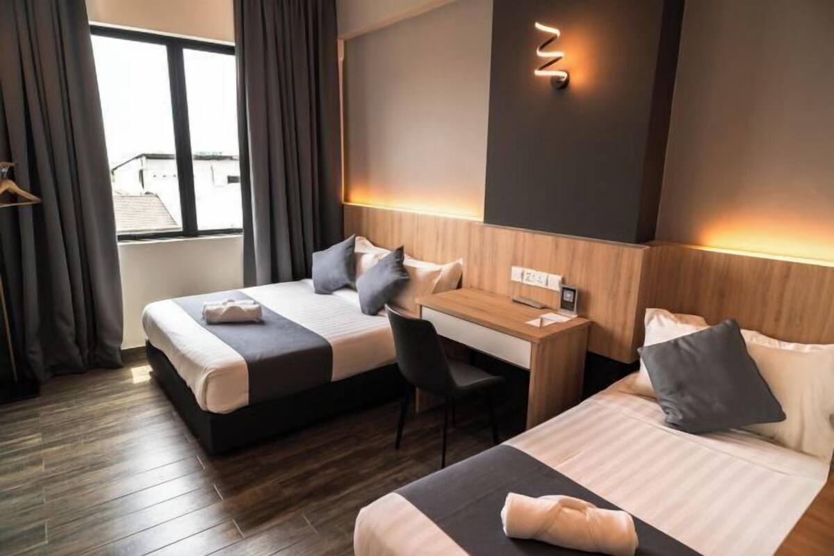 A hotel room with two beds, a desk, and a chair.