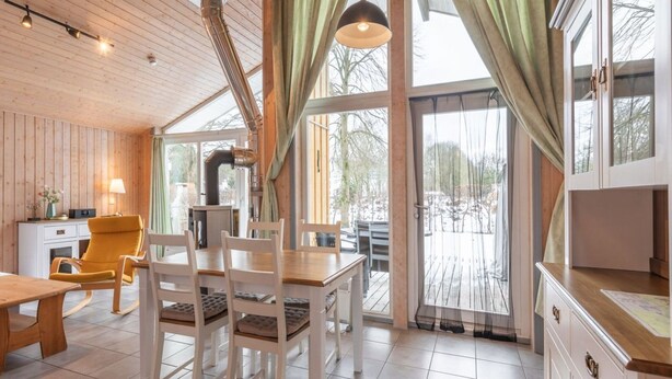Een gezellig cabin interieur met een eethoek, houten wanden en grote ramen.