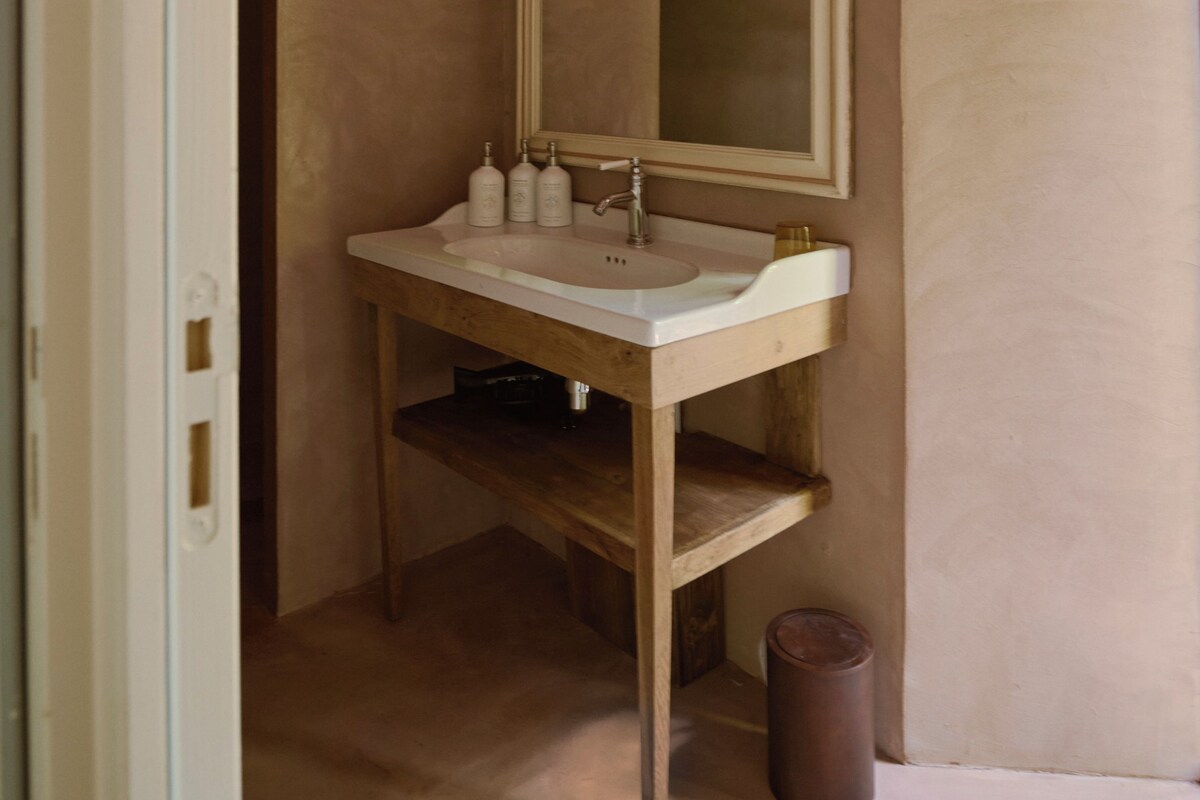 Une salle de bain avec un lavabo blanc, un miroir et des étagères en bois.