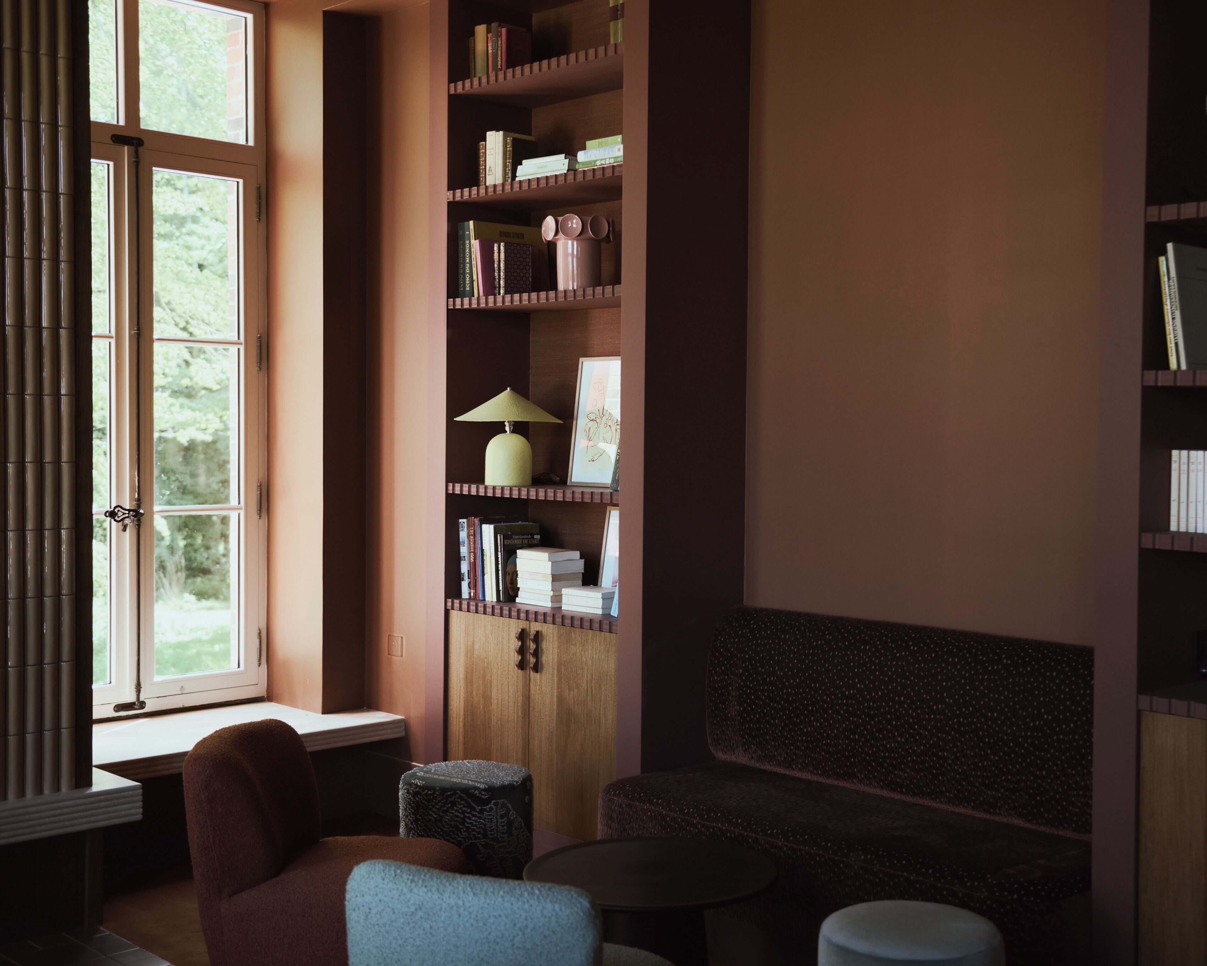 A cozy reading nook with a bookshelf, a lamp, and a bench.