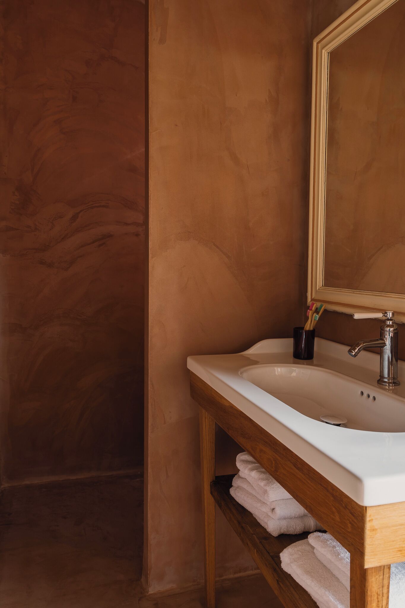 A bathroom with a wooden vanity, a white sink, and a mirror.