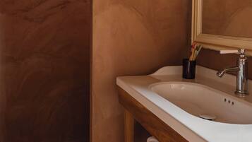 A bathroom with a wooden vanity, a white sink, and a mirror.