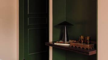 A room with a green door, a desk with a lamp, and a yellow chair.