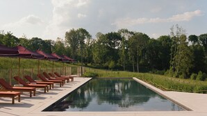 A swimming pool with lounge chairs and umbrellas, surrounded by trees and a clear sky. - Repère Sauvage, Hôtel Lodges & Restaurant (La Ville-aux-Clercs)