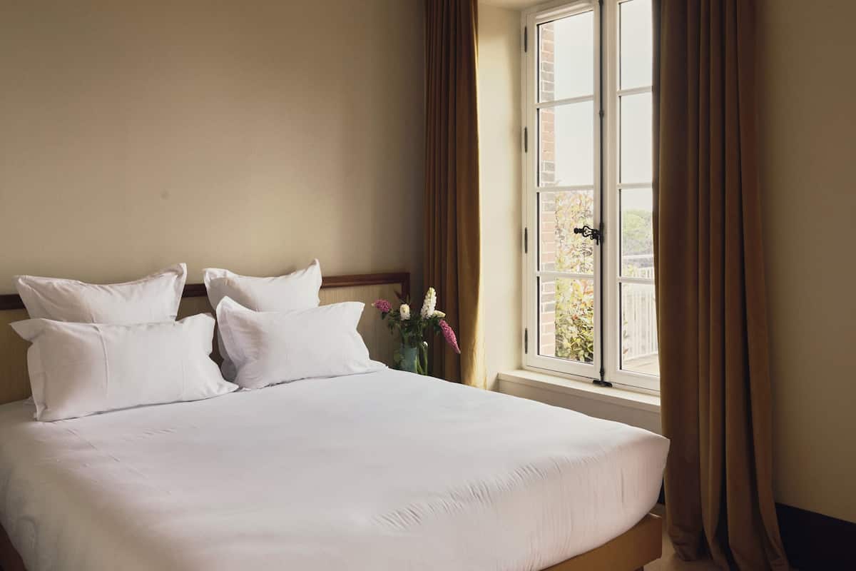 Una habitación de hotel con una cama grande, una ventana con cortinas y vistas al exterior.