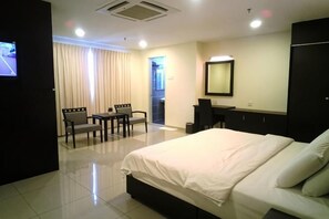A hotel room with a bed, a desk, a chair, a television, and a mirror. - villa hotel segamat (Segamat)