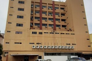 A multi-story building with air conditioning units, a garage, and parked cars. - villa hotel segamat (Segamat)