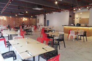 A modern dining area with tables and chairs, a bar area, and a brick wall. - villa hotel segamat (Segamat)