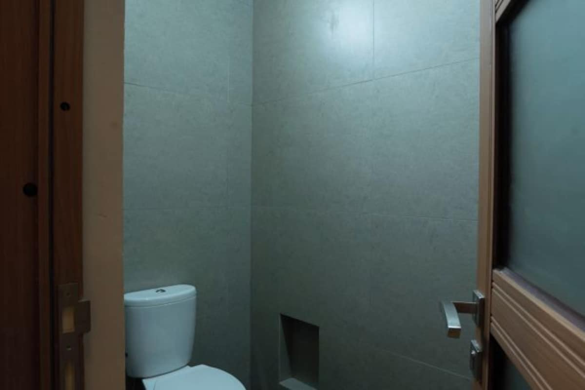 A narrow bathroom with a toilet and a shower area.