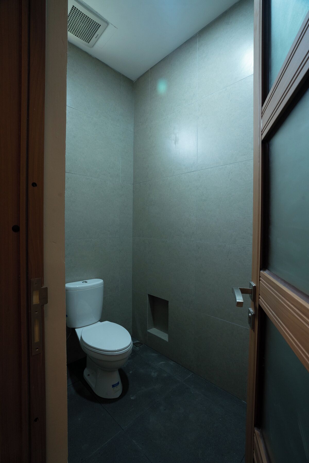 A small, narrow bathroom with a toilet and a shower stall.