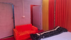 Een kamer met een bed, een rode bank en een gordijn.
