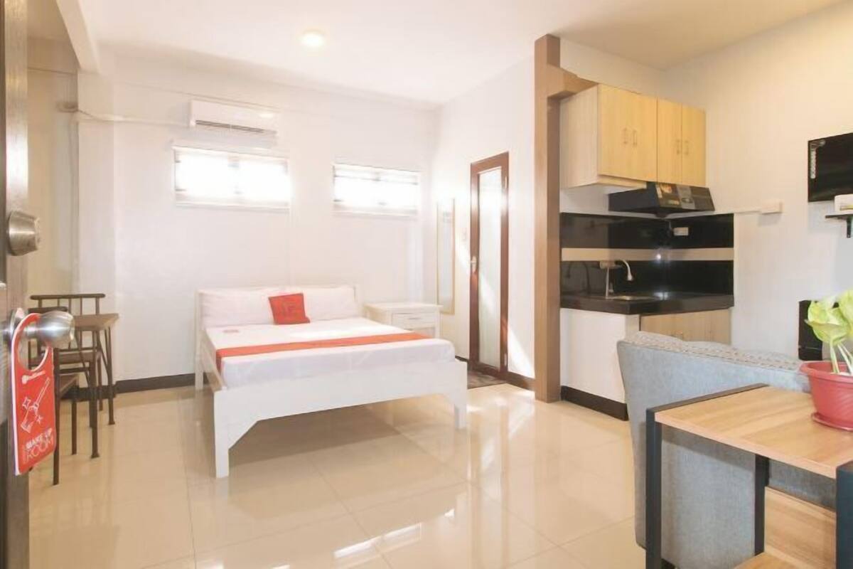 Habitación de hotel con cama, una mesita, kitchenette y baño.
