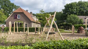 A garden with wooden play structures, a brick house, and a small dome structure.